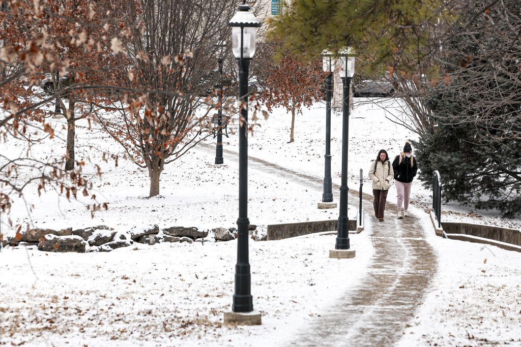 Two people walking on a sidewalk in the snow