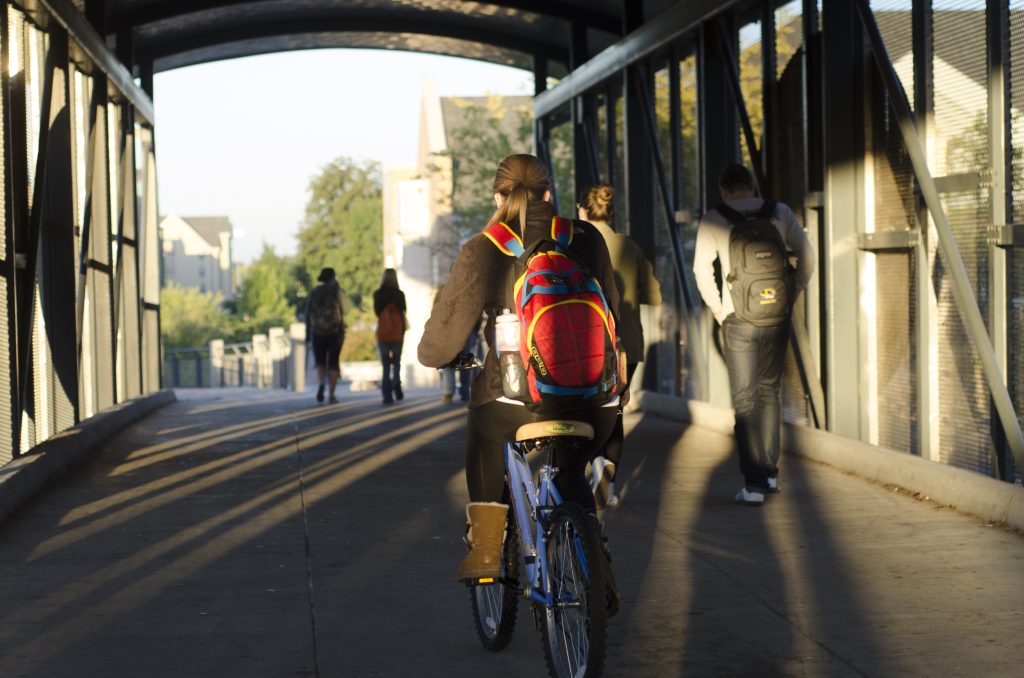 A person riding a bike through a tunnel with other people walking nearby